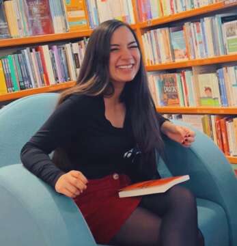Anahí Miranda sonriendo en una biblioteca